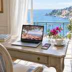A laptop and a phone on a writing desk in a Riviera hotel suite, showing QUIET wallpapers